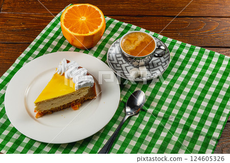 Cheesecake slice with coffee and orange on a checkered tablecloth 124605326