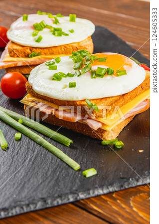 Delicious breakfast sandwich with egg and ham on dark slate plate 124605333