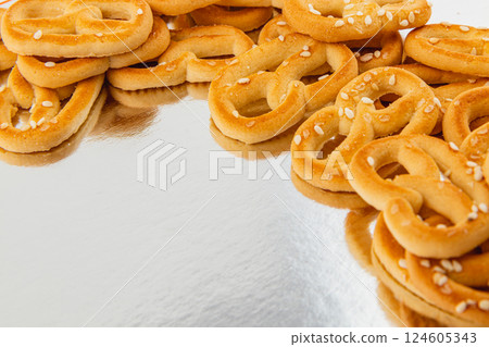 Delicious soft pretzels sprinkled with sesame seeds on a reflective surface Delicious soft pretzels sprinkled with sesame seeds on a reflective surface 124605343