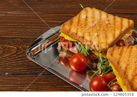 Grilled cheese sandwich with ham and fresh vegetables on a silver tray 124605358