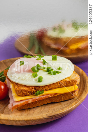 Delicious breakfast sandwich with egg, cheese, and ham on wooden plate Delicious breakfast sandwich with egg, cheese, and ham on wooden plate 124605387