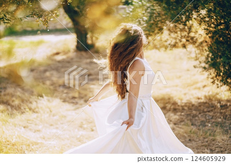 Beautiful long-haired bride in a magnificent white dress walking in nature Beautiful long-haired bride in a magnificent white dress walking in nature 124605929