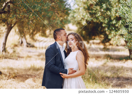 beautiful long-haired bride in white dress with her young man walking in the nature beautiful long-haired bride in white dress with her young man walking in the nature 124605930
