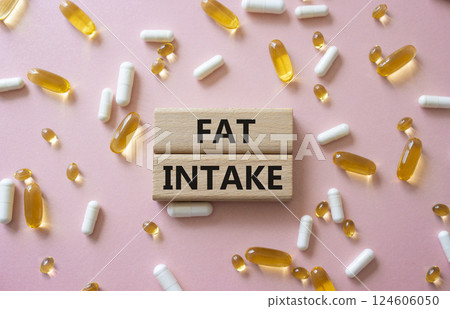 Fat Intake symbol. Concept word Fat Intake on wooden blocks. Beautiful pink background with pills. Medicine and Fat Intake concept. Copy space 124606050