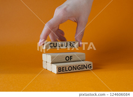 Culture of Belonging symbol. Wooden blocks with words Culture of Belonging. Businessman hand. Beautiful orange background. Business and Culture of Belonging concept. Copy space. 124606084