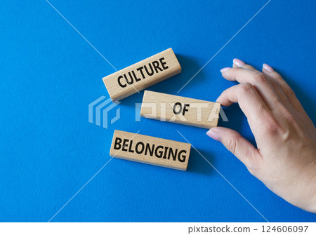 Culture of Belonging symbol. Wooden blocks with words Culture of Belonging. Businessman hand. Beautiful blue background. Business and Culture of Belonging concept. Copy space. 124606097