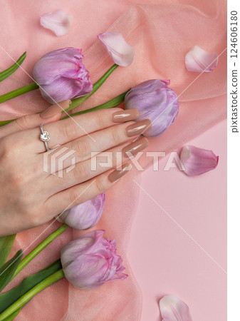 Woman showing stylish nude manicure with tulips on pink background 124606180