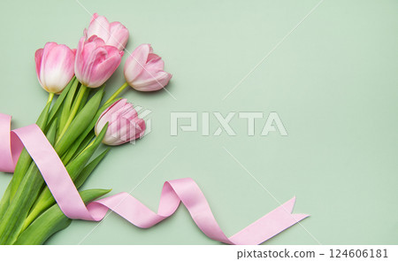 Pink tulips with ribbon on pastel green background for spring holidays 124606181