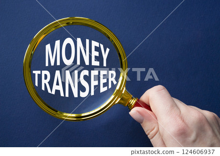 Money Transfer symbol. Magnifying Glass with Concept word Money Transfer. Businessman hand. Beautiful deep blue background. Business and Money Transfer concept. Copy space Money Transfer symbol. Magnifying Glass with Concept word Money Transfer. Businessman hand. Beautiful deep blue background. Business and Money Transfer concept. Copy space 124606937