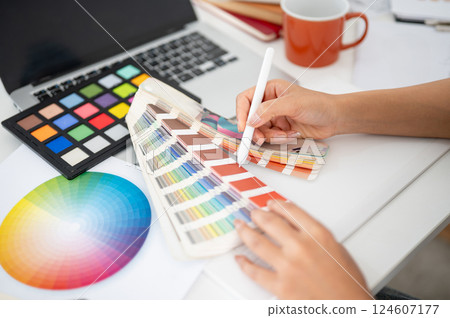 Close up of a hand pointing a stylus at a color palette. Designer choosing or picking a color. 124607177