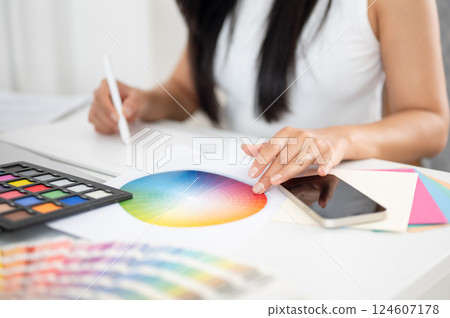 Close up of a hand with fingers touching on a color chart and holding a stylus drawing on tablet. Close up of a hand with fingers touching on a color chart and holding a stylus drawing on tablet. 124607178