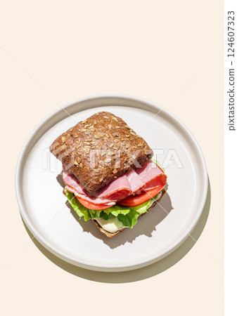 Toast sandwich made of grain bread with prosciutto, cheese, tomatoes, lettuce and sauce  124607323