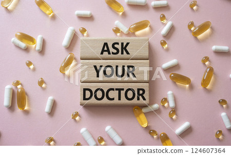 Ask Your Doctor symbol. Concept word Ask Your Doctor on wooden blocks. Beautiful pink background with pills. Medicine and Ask Your Doctor concept. Copy space 124607364