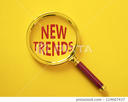 New Trends symbol. Magnifying glass with words New Trends. Beautiful yellow background. Business and New Trends concept. Copy space. 124607437