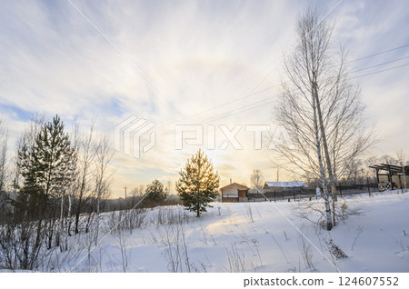 Sunset over forest hills covered with snow and country houses in the distance in winter Sunset over forest hills covered with snow and country houses in the distance in winter 124607552