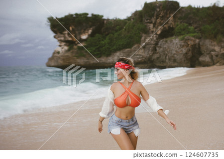 young attractive happy woman dancing twirling on seashore sunny summer fashion style in white shirt and swimsuit vacation young attractive happy woman dancing twirling on seashore sunny summer fashion style in white shirt and swimsuit vacation 124607735
