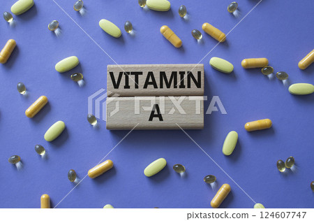Vitamin A symbol. Concept word Vitamin A on wooden blocks. Beautiful purple background with pills. Medicine and Vitamin A concept. Copy space 124607747