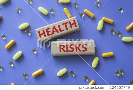Health Risks symbol. Concept word Health Risks on wooden blocks. Beautiful purple background with pills. Medicine and Health Risks concept. Copy space 124607749