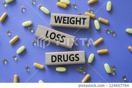 Medicine symbol. Concept words Weight Loss Drugs on wooden blocks. Beautiful purple background with pills. Medicine concept and Weight Loss Drugs. Copy space 124607764