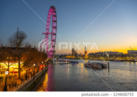 As twilight descends over London, the London Eye glows in shades of pink, reflecting on the River Thames. As twilight descends over London, the London Eye glows in shades of pink, reflecting on the River Thames. 124608735