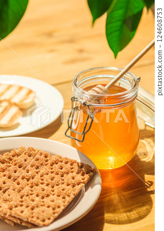 Honey Jar With Wooden Dipper Beside Crispy Bread and Toast on a Wooden Table, Highlighting Cafes and Wellness Shops 124608753