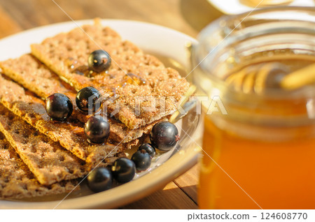 A Plate of Crunchy Crackers is Elegantly Presented With Fresh Berries and Honey, Bathed in Gentle Sunlight A Plate of Crunchy Crackers is Elegantly Presented With Fresh Berries and Honey, Bathed in Gentle Sunlight 124608770