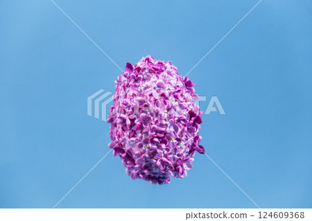Easter egg made of lilac spring flowers levitating in pastel blue background. Sustainable holiday minimalistic still life composition. Copy space template for invitation greeting card 124609368