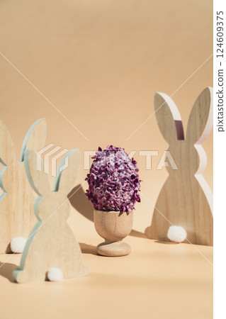Wooden minimalism low-key bunny decor. Easter egg made of lilac spring flowers in pastel beige background. Sustainable holiday minimalistic still life composition. Copy space template for invitation Wooden minimalism low-key bunny decor. Easter egg made of lilac spring flowers in pastel beige background. Sustainable holiday minimalistic still life composition. Copy space template for invitation 124609375