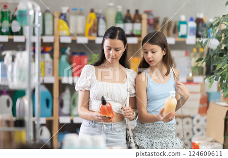 Woman with preteen daughter choosing liquid soap in store 124609611