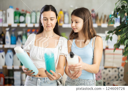 Woman with teen daughter choosing shampoo in hygiene store 124609726