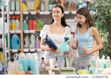Woman with daughter choosing cleaning spray Woman with daughter choosing cleaning spray 124609746