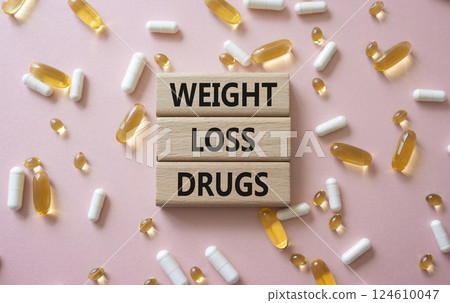 Medicine symbol. Concept words Weight Loss Drugs on wooden blocks. Beautiful pink background with pills. Medicine concept and Weight Loss Drugs. Copy space Medicine symbol. Concept words Weight Loss Drugs on wooden blocks. Beautiful pink background with pills. Medicine concept and Weight Loss Drugs. Copy space 124610047