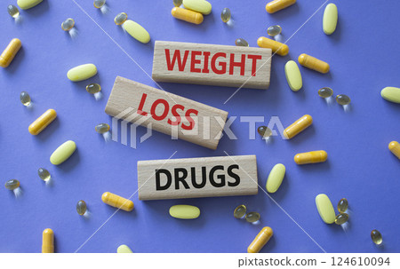 Medicine symbol. Concept words Weight Loss Drugs on wooden blocks. Beautiful purple background with pills. Medicine concept and Weight Loss Drugs. Copy space Medicine symbol. Concept words Weight Loss Drugs on wooden blocks. Beautiful purple background with pills. Medicine concept and Weight Loss Drugs. Copy space 124610094