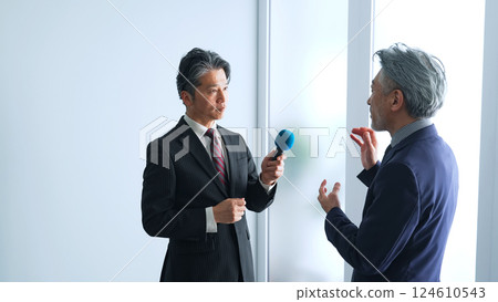 Middle-aged male reporter holding a microphone and interviewing 124610543