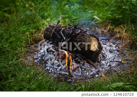 Burning fire in the evening, summer beautiful warm evening. The process of lighting a fire. Burning fire in the evening, summer beautiful warm evening. The process of lighting a fire. 124610720