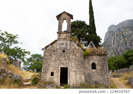 Ruined stone church stands overlooking a mountainous landscape in Montenegro, showcasing its weathered beauty and historical significance 124610767