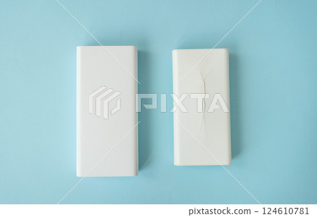 Two white power banks, one undamaged, one cracked, on a light blue background Two white power banks, one undamaged, one cracked, on a light blue background 124610781