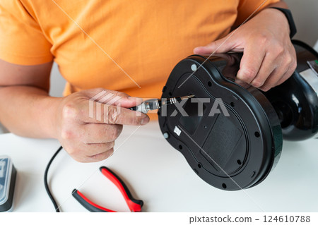 A person carefully repairs a broken appliance using a small screwdriver, demonstrating DIY home repair 124610788