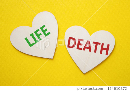 Life or Death symbol. Concept word Life or Death on wooden hearts. Beautiful yellow background. Business and Life or Death concept. Copy space 124610872