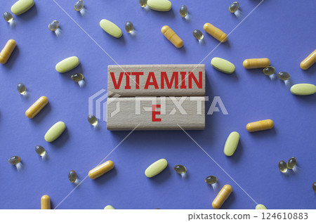 Vitamin E symbol. Concept word Vitamin E on wooden blocks. Beautiful purple background with pills. Medicine and Vitamin E concept. Copy space 124610883