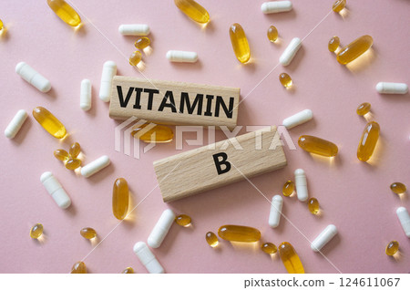 Vitamin B symbol. Concept word Vitamin B on wooden blocks. Beautiful pink background with pills. Medicine and Vitamin B concept. Copy space 124611067