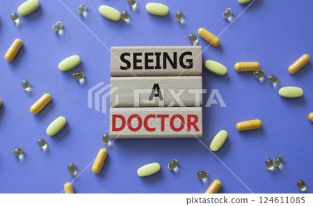 Seeing a Doctor symbol. Concept word Seeing a Doctor on wooden blocks. Beautiful purple background with pills. Medicine and Seeing a Doctor concept. Copy space 124611085