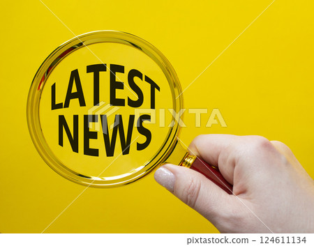 Latest News symbol. Concept word Latest News on magnifying glass. Businessman hand. Beautiful yellow background. Business and Latest News concept. Copy space 124611134