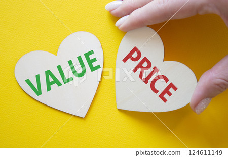 Price and Value symbol. Concept word Price and Value on wooden hearts. Businessman hand. Beautiful yellow background. Business and Price and Value concept. Copy space Price and Value symbol. Concept word Price and Value on wooden hearts. Businessman hand. Beautiful yellow background. Business and Price and Value concept. Copy space 124611149