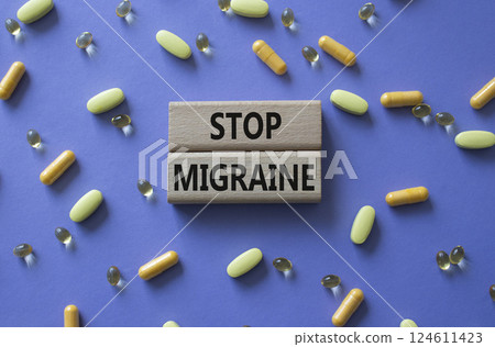 Stop Migraine symbol. Concept word Stop Migraine on wooden blocks. Beautiful purple background with pills. Medicine and Stop Migraine concept. Copy space 124611423