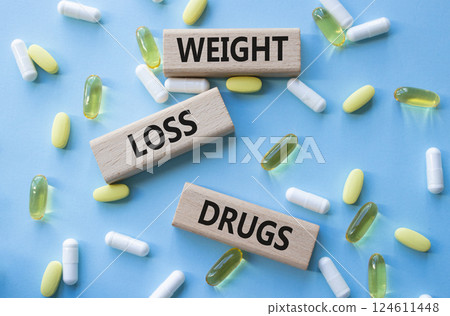 Medicine symbol. Concept words Weight Loss Drugs on wooden blocks. Beautiful blue background with pills. Medicine concept and Weight Loss Drugs. Copy space 124611448