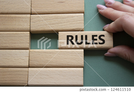 Rules symbol. Wooden blocks with word Rules. Businessman hand. Beautiful grey green background. Rules concept. Copy space. Rules symbol. Wooden blocks with word Rules. Businessman hand. Beautiful grey green background. Rules concept. Copy space. 124611510