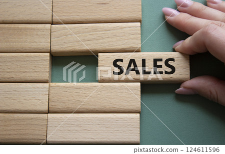 Sales symbol. Concept word Sales on wooden blocks. Businessman hand. Beautiful grey green background. Business and Sales concept. Copy space. Sales symbol. Concept word Sales on wooden blocks. Businessman hand. Beautiful grey green background. Business and Sales concept. Copy space. 124611596
