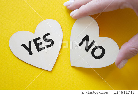 Yes or No symbol. Concept word Yes or No on wooden hearts. Businessman hand. Beautiful yellow background. Business and Yes or No concept. Copy space 124611715