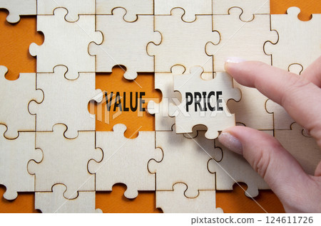 Price and Value symbol. Concept word Price and Value on wooden puzzle. Businessman hand. Beautiful orange background. Business and Price and Value concept. Copy space Price and Value symbol. Concept word Price and Value on wooden puzzle. Businessman hand. Beautiful orange background. Business and Price and Value concept. Copy space 124611726